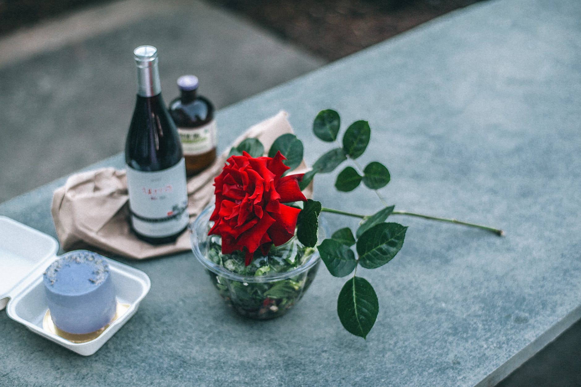 composition of red rose placed on parapet near champagne bottle